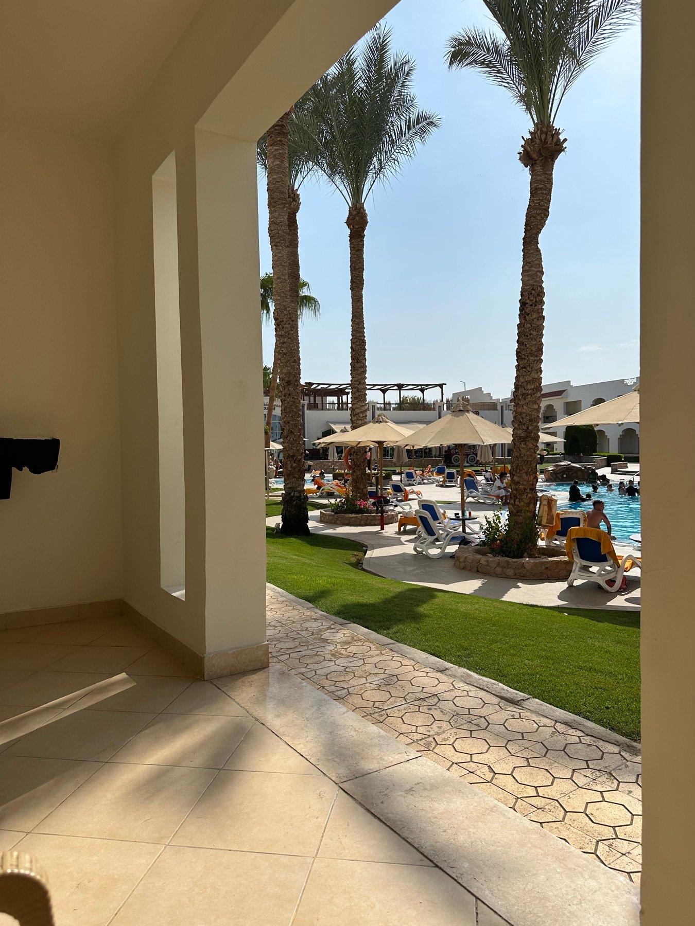 Blick durch einen schattigen Durchgang auf Palmen und einen Resortgarten in Ägypten